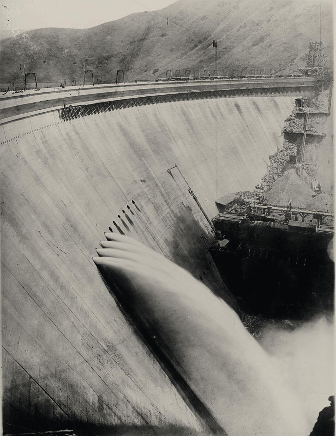 Arrowrock Dam, around 1915–25: water blasting from its outlet valves down the curved concrete face.